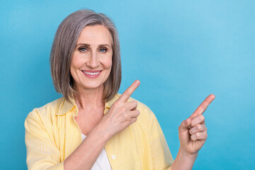 Sticker - Photo of cute cheerful lady wear yellow shirt pointing two fingers empty space isolated blue color background