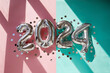 Silver numbers 2024 new year balloons among confetti in sunlight on pink turquoise background Happy new year celebration party. Greetings and congratulation