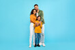 Healthy family relationship. European dad and mom embracing daughter, posing over blue background, full length