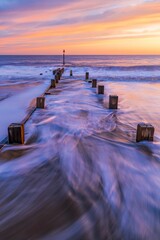 Poster - Ethereal long exposure of a pier at sunrise with waves crashing against it