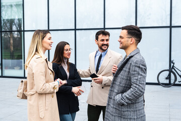 Wall Mural - Group of business people walking outside in front of office building. Colleagues discussing on the way to the work. Young employees talking about staff meeting.