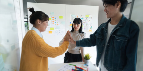 Wall Mural - asia team creative in smart casual wear discussing phone application design celebrate giving five af