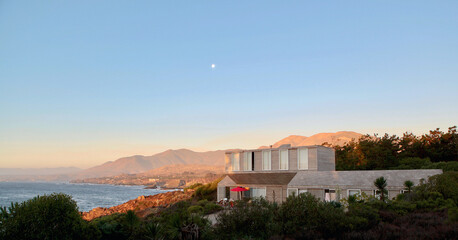 Wall Mural - the house overlooking the ocean and mountain range at sunset