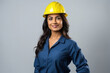 © PRASANNAPIX - Young and confident female engineer wearing hard hat standing on white background.
