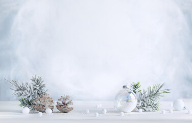 Wall Mural - Christmas still life with snowy pine cones, baubles and  fir branches on light background. Winter or Christmas festive concept.