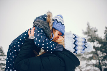 Little girl with mother playing in a winter park