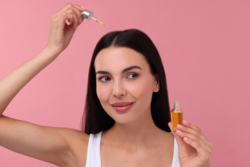 Sticker - Beautiful woman applying hair serum on pink background. Cosmetic product