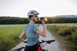 © Halfpoint - Diabetic cyclist with a continuous glucose monitor on her arm drinking water during her bike tour.