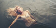 Mystical image of unconscious blonde woman floating in cold lake waters, evokes a powerful emotional response and intrigue. Ideal for artistic projects.