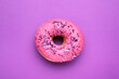 Leinwandbild Motiv Sweet glazed donut decorated with sprinkles on purple background, top view. Tasty confectionery
