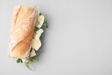 Tasty sandwich with brie cheese on light grey background, top view. Space for text