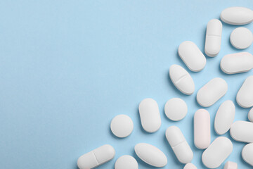 Wall Mural - Many pills on light blue background, flat lay. Space for text