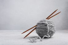 Gray Clew Of Yarn With Wooden Knitting Needles