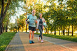 Full length image of beautiful sporty healthy active cheerful middle age couple going to exercise outdoors in park holding mats for yoga, pilates, gym. Sports healthy lifestyle. Loving older couple..