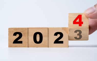 Wall Mural - hand flipping of 2023 to 2024 on wooden block cube for preparation new year change and start new bus