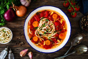 Tomato soup with noodles on wooden table