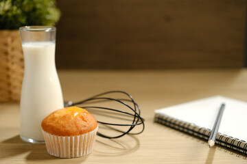 homemade muffins in white paper muffin cups and a glass of milk on the table.