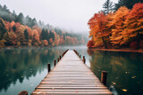 Fototapeta  - A dock with wooden path on a lake with autumn forest landscape. Beautiful fall nature background, calm blue water in the river.