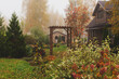 old rustic wooden country house with archway in foggy fall day. Autumn natural garden view.