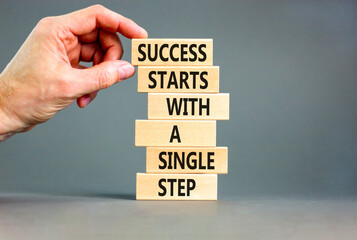 Wall Mural - Success symbol. Concept words Success starts with a single step on wooden block. Beautiful grey table grey background. Businessman hand. Business success starts with single step concept. Copy space.