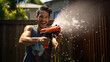 © Studio Nova - Man playing with a water gun in his front yard on a warm summer afternoon