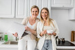 © LIGHTFIELD STUDIOS - two blonde attractive sisters with laptop and tea cup looking at camera, quality time, bonding