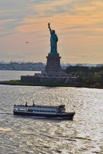 A Sightseeing Boat Passes By The Statue Of Liberty On The Hudson River As A Helicopter Flies By The Statue.