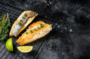 Wall Mural - Grilled sea bass fillet with lime and thyme. Black background. Top view. Copy space