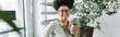 © LIGHTFIELD STUDIOS - happy african american businesswoman in glasses holding paper cup with coffee in office, banner