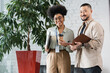 © LIGHTFIELD STUDIOS - cheerful interracial office workers looking at camera during coffee break, corporate diversity