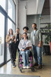 © LIGHTFIELD STUDIOS - group shot of diverse startup team looking at camera in office, wheelchair user, inclusion concept