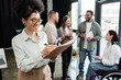 © LIGHTFIELD STUDIOS - cheerful african american woman taking notes and standing near interracial team in coworking