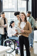 © LIGHTFIELD STUDIOS - happy businesswoman with tablet near blurred interracial startup team, diversity and inclusion