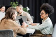 © LIGHTFIELD STUDIOS - happy interracial female colleagues talking in modern coworking, project planning and collaboration