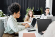 © LIGHTFIELD STUDIOS - side view of african american businesswoman using laptop near female colleagues in office