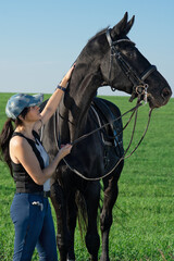 Wall Mural -  beautiful black dressage  horse  with his owner and rider  posing in green grass meadow after training. sunny day