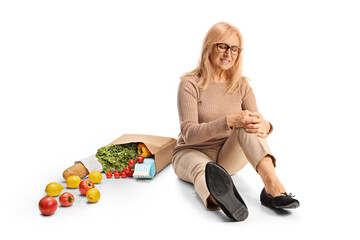 Woman with a grocery bag and injured knee sitting on ground