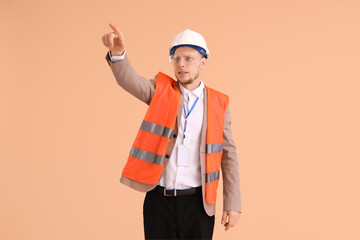 Wall Mural - Male architect in vest pointing at something on beige background