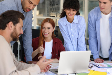 Canvas Print - Team of employees working together at table in office. Startup project