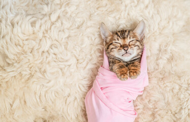 Aufkleber - Tiny newborn bengal kitten wrapped like a baby sleeps on a fur bed. Top down view. Empty space for text