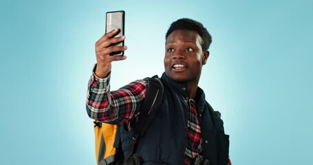 Poster - Hiking, video call and black man with backpack in studio for travel, adventure and freedom on blue background. Smartphone, conversation and guy backpacking influencer with social media live streaming