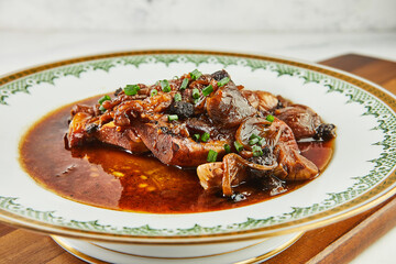 Wall Mural - Ossobuco with garlic and green onions in red wine on plate with an ornament