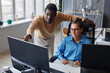 © AnnaStills - Young man pointing at monitor and discussing new computer program with his colleague in office