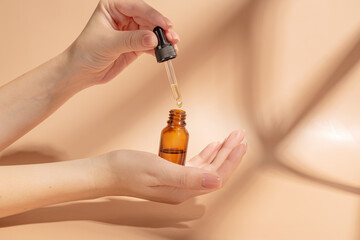 female hand with dropper of essential oil, aromatherapy essence, beauty serum or medicinal liquid on