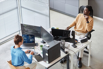 high angle view of colleagues writing computer codes on computers during their work in it office