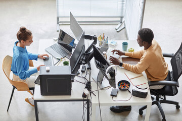 high angle view of couple of programmers typing codes on computers in it office