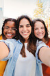 © Jose Calsina - Vertical portrait of a group of girls. Happy multiracial female teenagers having fun smiling taking a selfie together. Multiethnic young women friends laughing and taking a photo with a smartphone