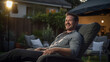 © AspctStyle - Portrait of a smiling man sitting and watching a movie in a backyard home cinema