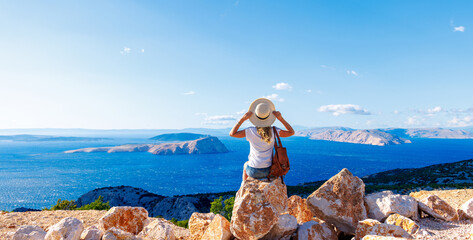 Wall Mural - woman sitting on rock enjoying panoramic view of sea and islands- travel, vacation,adventure, touris