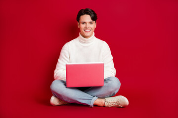 Canvas Print - Full length portrait of positive nice man sit floor use wireless netbook isolated on red color background